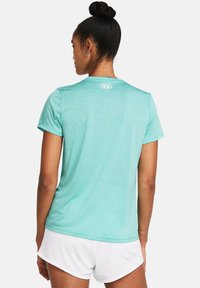 Kortsleeve teal treningsskjorte med rund hals og en hvit logo på ryggen, kombinert med hvite mesh-shorts. Glatt stofftekstur.