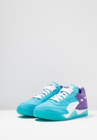 Turquoise and purple sneakers made of suede and rubber; features white laces, iconic logo, and a thick, textured sole.