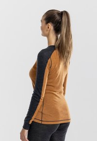 Long-sleeve top featuring a black and orange color block design, with a textured finish and contrasting stitching along the seams.