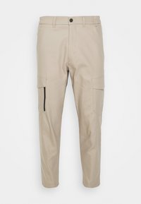 Beige cargobyxor med slim fit, framfickor och en sidoficka med dragkedja. Tillverkade av ett slätt, hållbart tyg med en något avsmalnande ben.