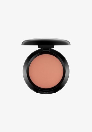 Compact de blush rond avec une finition noire mate. L'intérieur révèle une poudre douce de teinte pêche avec une texture de surface nervurée. Le couvercle est partiellement ouvert.
