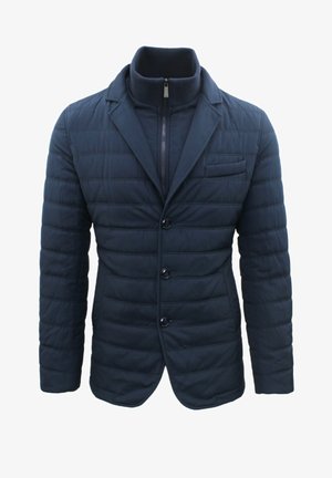 Blazer trapuntato blu navy con colletto alto, chiusura frontale con zip e tre bottoni. Presenta una tasca sul petto e due tasche laterali. Tessuto testurizzato.