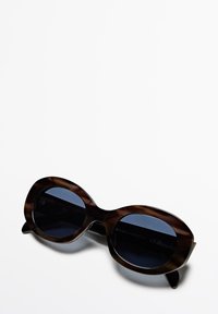 Occhiali da sole tartarugati marrone con lenti ovali e tinta blu scura. Stecche sottili con leggero curvatura alle estremità. Etichetta di protezione UV visibile.