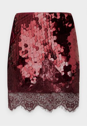 Kurzer roter Paillettenrock mit glänzender, strukturierter Oberfläche, Spitzenbesatz am Saum und gewellter Kante, der glänzende Pailletten mit filigranen Spitzendetails kombiniert.