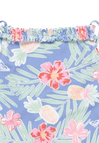 Blå tropisk tyg med rosa och röda blommor, gröna blad och gula ananaser. Rynkad volang längs den övre kanten.