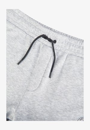 Lichtgrijze sweatpants met een zwarte trekkoord, los gestrikt, en zichtbare stiksels van de zijzak.