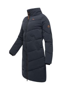 Tamsiai mėlynas ilgas pūkinis paltas su stovinčiu apykakliu, priekiniais užtrauktuku, šoninėmis kišenėmis, ribotomis rankogaliais ir logotipo pleistru kairėje rankovėje.