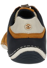 Achteraanzicht van een schoen met een marineblauwe en tan leren bovenwerk, witte zool, gevoerde kraag en gestructureerde accenten in een casual ontwerp.