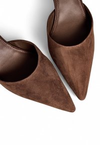 Rjave semširane mule s koničastim nosom in odprtim zadnjim delom, z gladkim notranjim oblogom, ki se ponašajo s sleek silhueto in minimalnimi šivi.