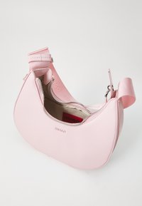 Sac à main en cuir rose avec un design courbé, fermeture zippée en haut et texture lisse. Présente un logo en relief et une bandoulière pour le port.