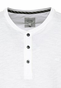 Witte biologische katoenen henley-shirt met een ronde halslijn, drie zwarte knopen en een subtiel textuurpatroon. Verfraaid met een zwarte afwerking.