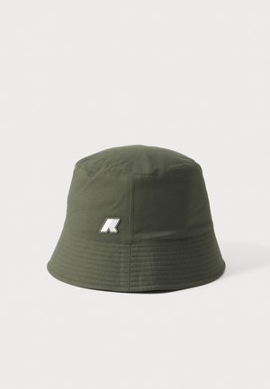 Grøn stof bucket hat med syet kant og lille hvidt logo foran mod en ensfarvet lys baggrund.