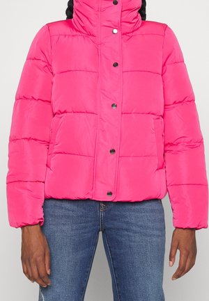 Veste puffer matelassée rose vif avec des boutons pression et des poches avant, portée avec un jean bleu, visible des épaules aux hanches.