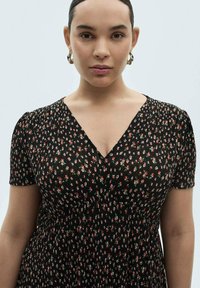 Rochie neagră cu mâneci scurte, având un model floral în roșu și alb. Design cu decolteu în V și textură pliată pe tot materialul.
