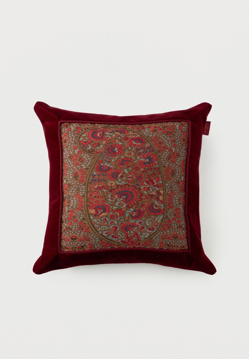 Coussin carré avec une bordure en velours rouge foncé et un panneau central présentant un motif complexe de tapisserie florale paisley en rouge, bleu et marron.