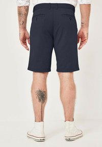 Marineblaue Shorts mit geradem Schnitt, aus leichtem Stoff gefertigt. Verfügt über zwei Gesäßtaschen mit Knopfverschluss und einem sauberen Saum.