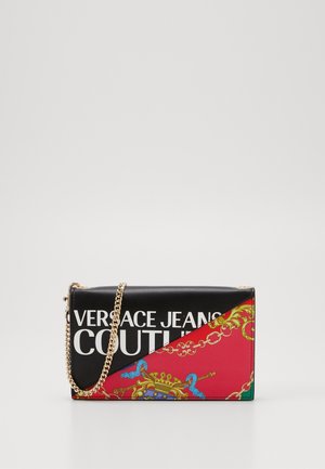Schwarze und rote Handtasche mit goldener Kettenriemen, mit einem aufgedruckten Design und dem fetten Text "VERSACE JEANS COUTURE" auf der Vorderseite.