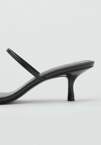 Černé otevřené sandály mají minimalistický design s tenkými řemínky a štíhlým, zúženým podpatkem. Povrch je hladký.