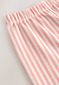 Tela a rayas rosa y blanca con superficie texturizada. La cintura elástica presenta detalles fruncidos. La tela tiene un aspecto suave y tejido.