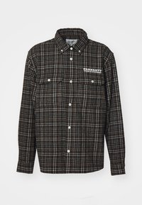 Chemise en flanelle à carreaux noirs et marron avec un col pointu, des manches longues, deux poches sur la poitrine et un logo blanc sur le côté gauche.
