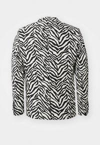 Schwarz-weiße Zebra-Print-Jacke, lange Ärmel, taillierte Gestaltung, strukturiertes Material, mit einer zentralen Naht entlang des Rückens.