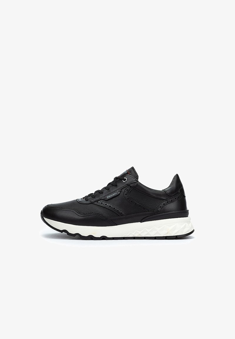 Zapatillas negras con upper de cuero texturizado, paneles de malla y detalles perforados. Presentan una suela blanca texturizada y cordones redondos.