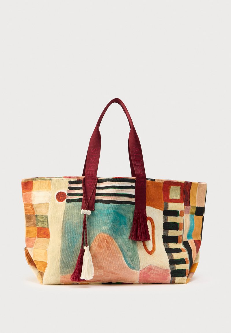 Canvas tote bag featuring a colorful abstract pattern with red and beige accents, topped with burgundy straps and decorative tassels.