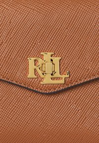 Brown textured wallet featuring a gold logo clasp and a sleek design with an envelope-style flap, outlined in dark stitches.