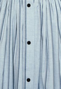 Gonna blu chiaro con righe verticali in blu scuro e marrone, caratterizzata da bottoni neri e pieghe per aggiungere texture e volume.