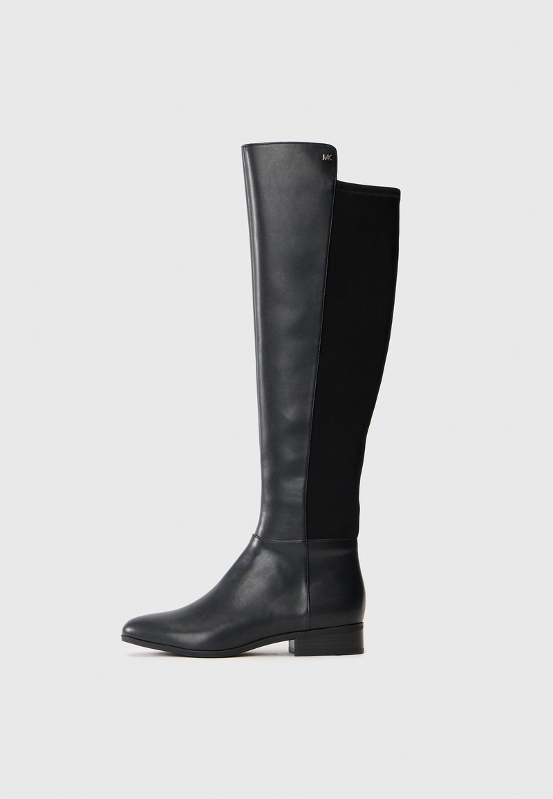 Bota de cuero negra hasta la rodilla con panel trasero de tela elástica, tacón bajo en bloque y pequeño logo metálico de la marca cerca del borde superior.