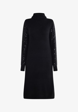 Czarna sukienka z długimi rękawami i wysokim kołnierzem. Materiał jest gładki, część ciała ma prążkowaną strukturę, a rękawy zdobione są czarnymi cekinami i prążkowanymi mankietami. Klasyczny fason w kształcie litery A.