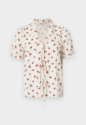 Blomstret kortermet bluse i off-white stoff med en krøllet tekstur. Har røde blomster og en knytefeste foran.