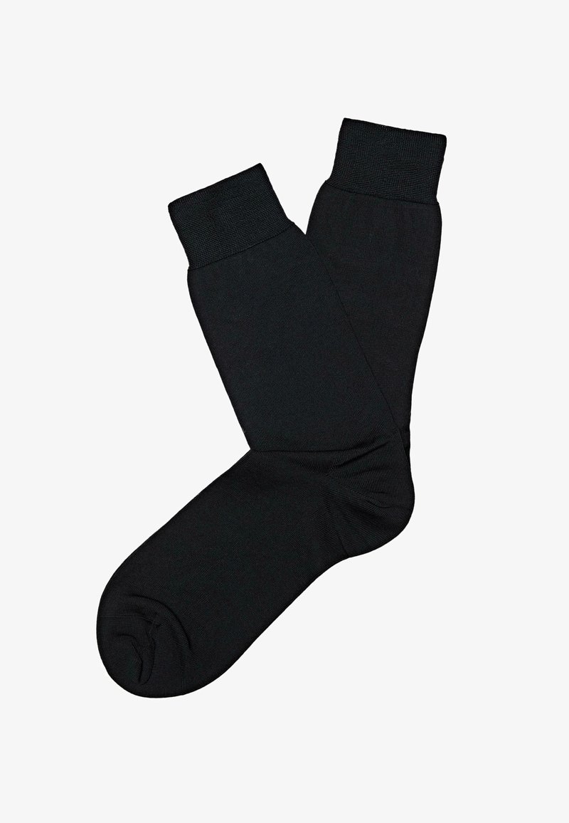 Paire de chaussettes noires unies, longueur mollet, avec des bords côtelés, étalées à plat sur un fond blanc.