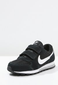 Czarne buty sportowe z siateczkową cholewką i zamszowymi akcentami, z dwiema regulowanymi taśmami, białym logo w kształcie „swoosh” oraz amortyzującą podeszwą.