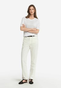 Lettet grå strik top med korte ærmer, parret med off-white lige bukser og sorte vævede sandaler med ankelrem.