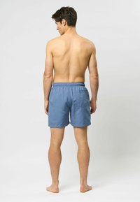 Šviesiai mėlyni maudymosi šortai su elastine juosta, užpakaliniu kišeniu ir laisvu siluetu. Pagaminti iš lygaus, greitai džiūstančio audinio.