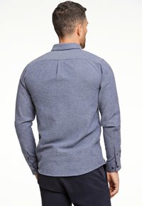 Heren overhemd met lange mouwen in een gestructureerde, donkerblauwe stof. Voorzien van een kraag, knoopmanchetten en een rechte zoom.