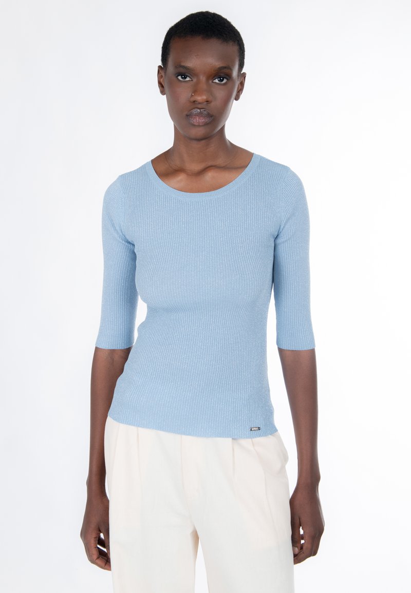 Hellblaues, geripptes Strickoberteil mit dreiviertel Ärmeln und einem breiten, rundgeformten Ausschnitt. Kleines Logo am Saum. Glatte Textur.