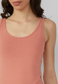 Perzikkleurige tanktop met een ronde halslijn en smalle schouderbandjes, gemaakt van een gladde, lichte stof met een slim fit ontwerp en minimale naadjes.