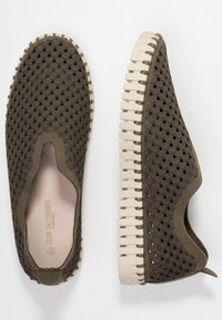 Scarpe slip-on verde oliva con un motivo a onde testurizzato, suola in gomma beige con righe e un'apertura rotonda per una facile vestibilità.