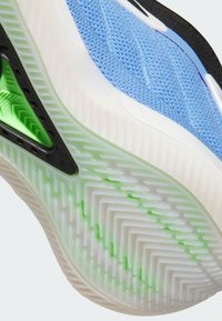 Buty sportowe z jasnoniebieską siateczką, czarnymi akcentami, białą podeszwą z zielonymi elementami i fakturowanym wzorem bieżnika.