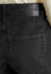 Zwarte denim jeans met een gestructureerde afwerking, achterzak en een leren label op de tailleband met de opdruk "Marc O'Polo DENIM."