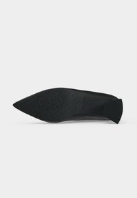 Semelle de chaussure noire à bout pointu avec motif texturé présentant le logo "BIANCO" répété et un petit talon bloc.