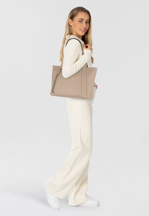 Sac cabas en cuir beige avec une forme structurée, doté d'une fermeture éclair sur le côté et de doubles poignées. Texture lisse, design minimaliste avec des accents subtils.