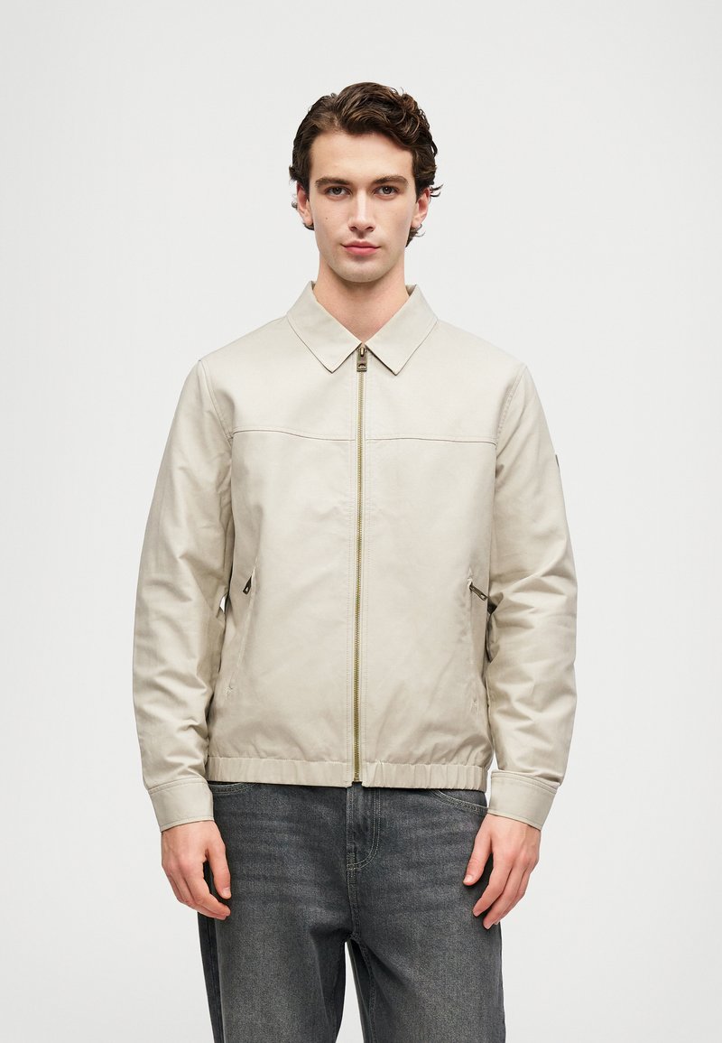 Šviesiai kremas švarkas su užtrauktuku priekyje ir apykakle, su dviem �šoninėmis kišenėmis. Pagamintas iš lygaus audinio, su elastingomis rankogaliais ir apatine dalimi.