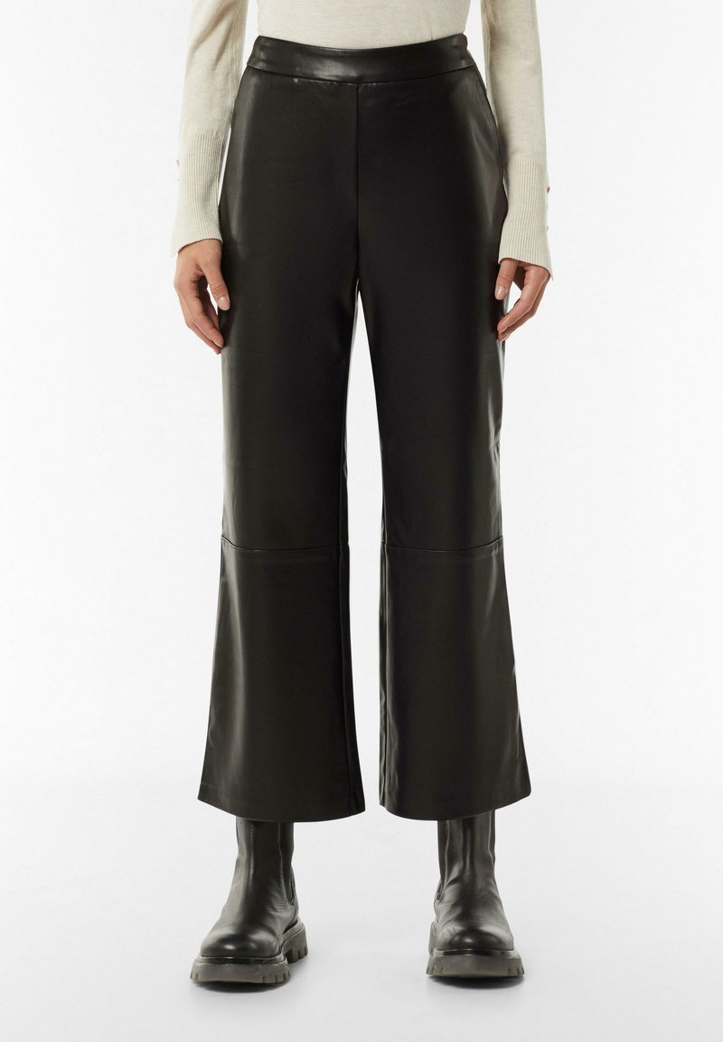 Zwarte faux leren wijde broek met een hoge taille, voorzien van stiksel-details en een gladde textuur. Gecombineerd met robuuste zwarte laarzen.