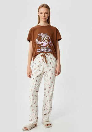 Brown cotton t-shirt with “COWGIRL” graphic and cow-print boots. White pajama pants with printed accents of boots and stars; elastic waist, drawstring.