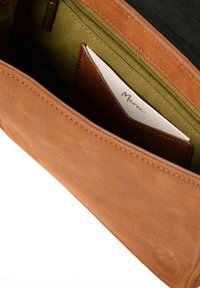 Bruine leren portemonnee met een gladde textuur. Voorzien van een groene stoffen voering aan de binnenkant, een met rits gesloten vak en een kaartenvak met een witte kaart.