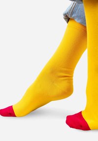 Żółte skarpetki sięgające za kolano o gładkiej fakturze, z jaskrawoczerwonymi akcentami w okolicach palców i mankietów.