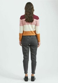 Pull en maille avec rayures roses, blanches et orange ; jean gris ; chaussures noires ; vue de dos ; texture moyenne, coupe décontractée.